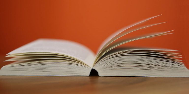 Libro abierto con fondo naranja vibrante