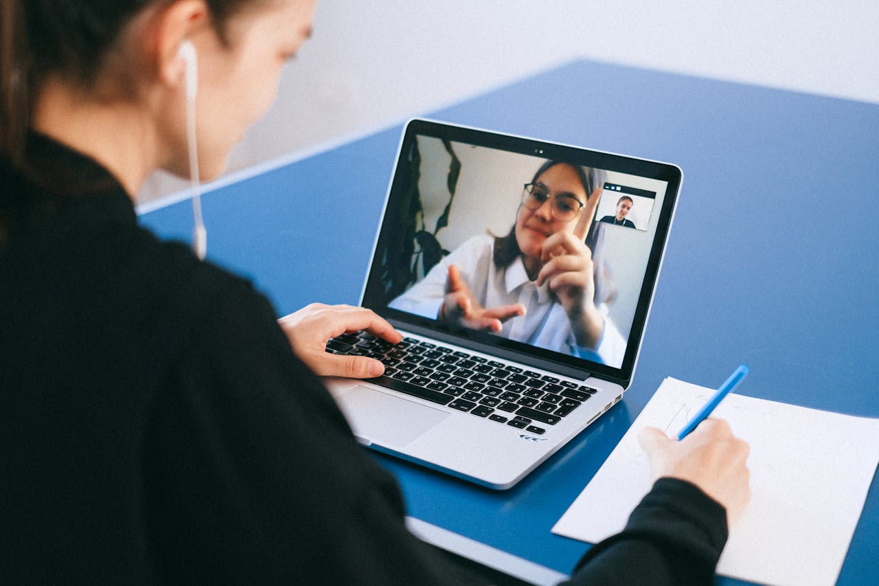 Mujer en videollamada con profesora durante una clase virtual.
