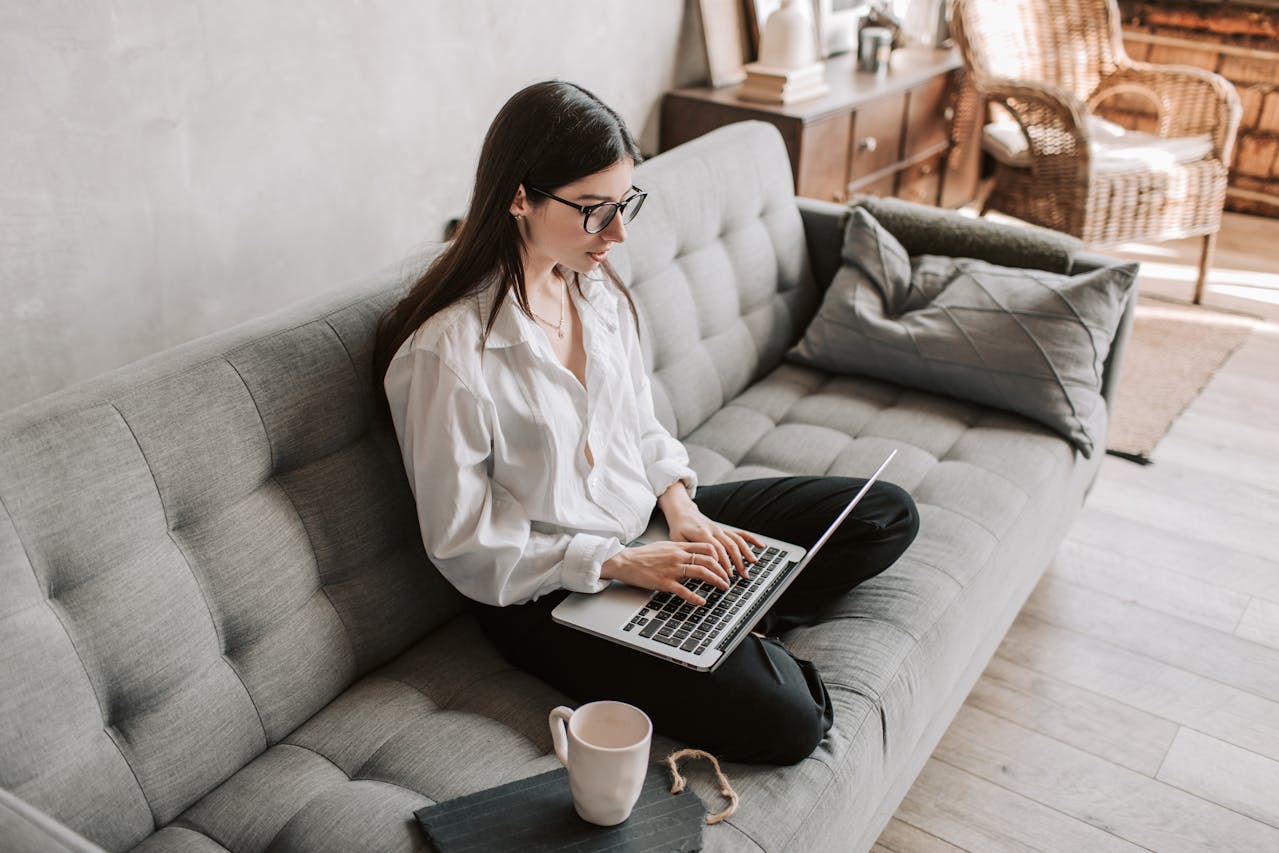Mujer joven trabajando en laptop sobre sofá