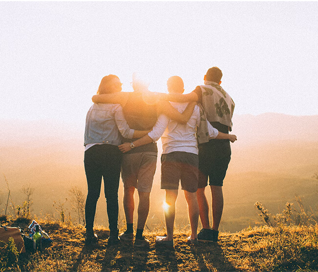 Grupo de amigos abrazados al atardecer